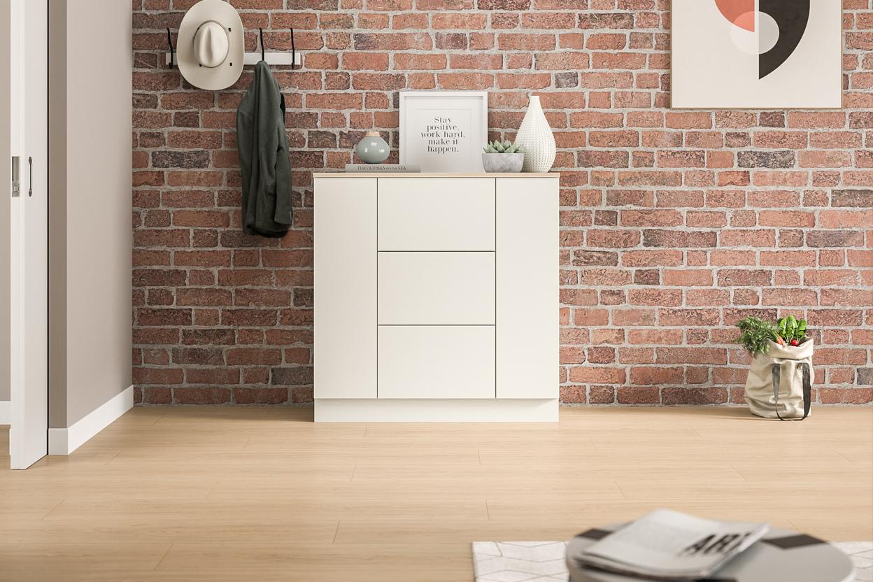Eine schlichte, weiße Kommode nach Maß, die sich gegen eine rustikale Backsteinwand abhebt, bietet Stauraum und eine stilvolle Ablagefläche im Eingangsbereich.