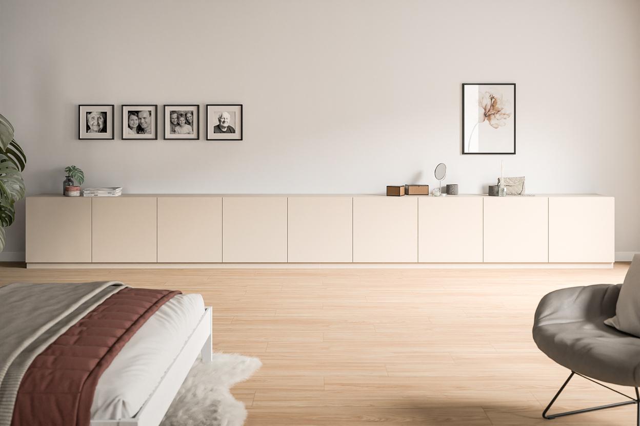 Langes, cremefarbenes Sideboard nach Maß in einem hellen Zimmer Niedriges, maßgefertigtes Sideboard in Creme, unter einer Wandgalerie aus Familienfotos, ergänzt durch minimalistische Dekoration.