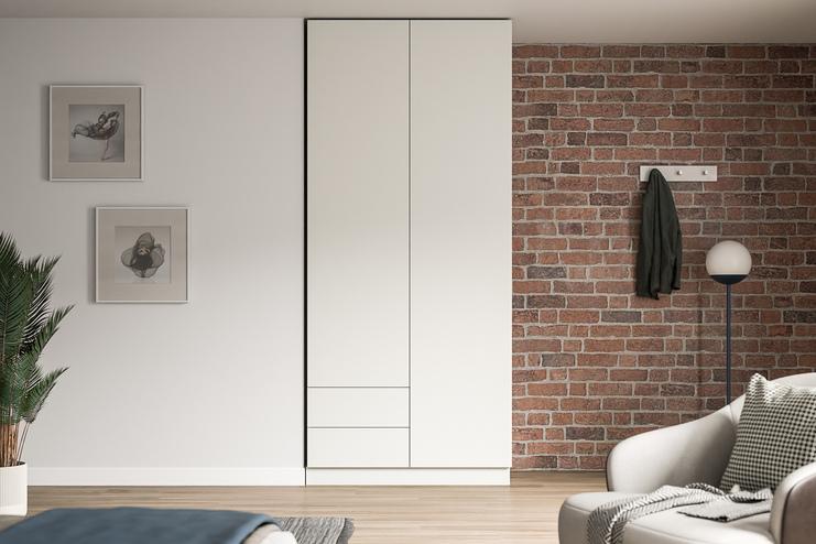 Großer, maßgeschneiderter weißer Schrank im Kontrast zu einer Ziegelwand, neben Kunstwerken und einer stilvollen Stehlampe.