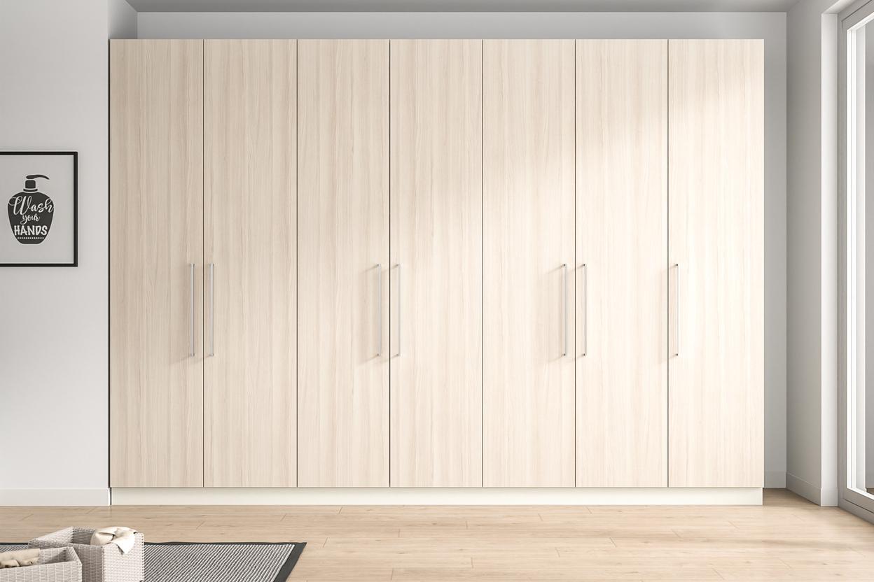 Wandfüllender, maßgeschneiderter Schrank in heller Holzoptik mit minimalistischen Griffen, der nahtlos in das moderne Raumdesign integriert ist.